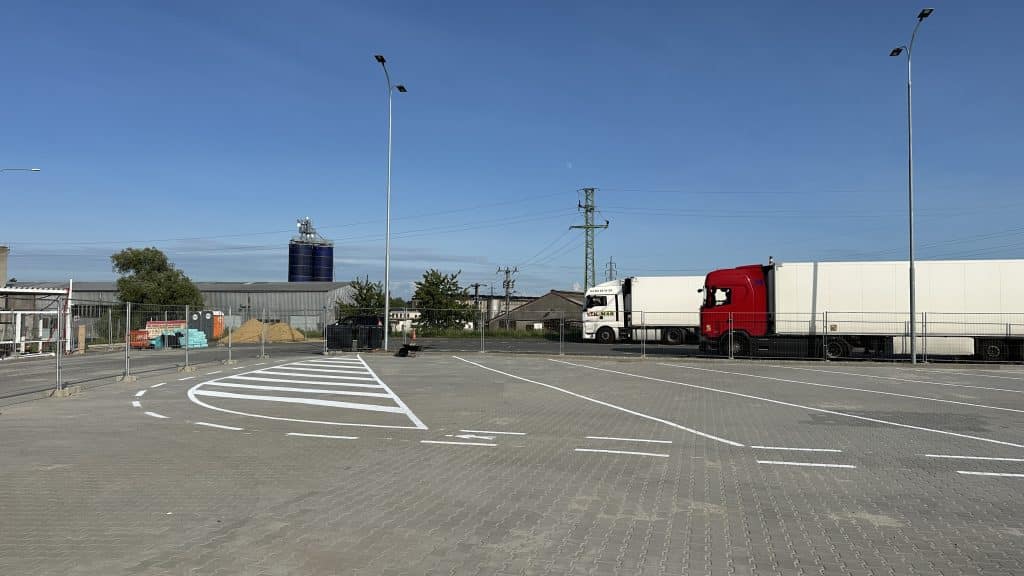 Realizace vodorovného dopravního značení bílou barvou - šikmé rovnoběžné čáry, čáry přerušované, směrové šípky, šikmé stání a symboly.